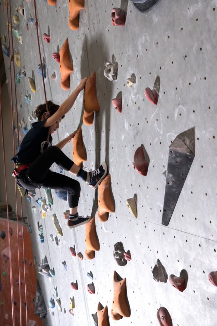 Child rock climbing on indoor wall showing coordination and motor skills development